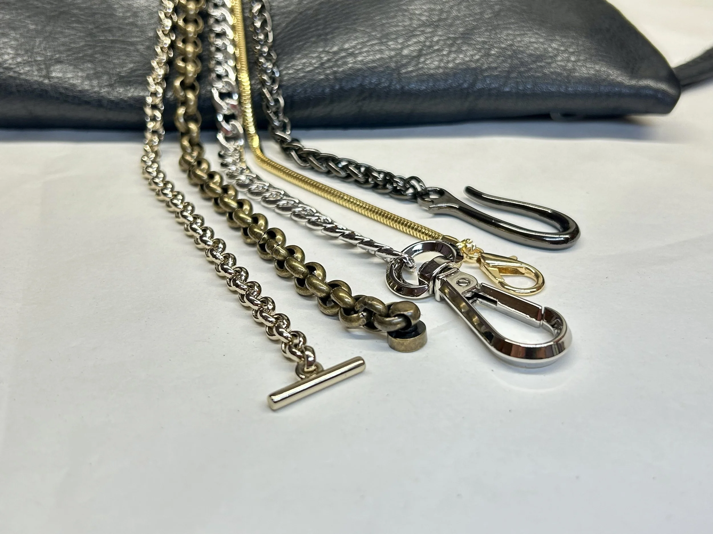 Braccialetti metallici davanti a una borsa di pelle nera