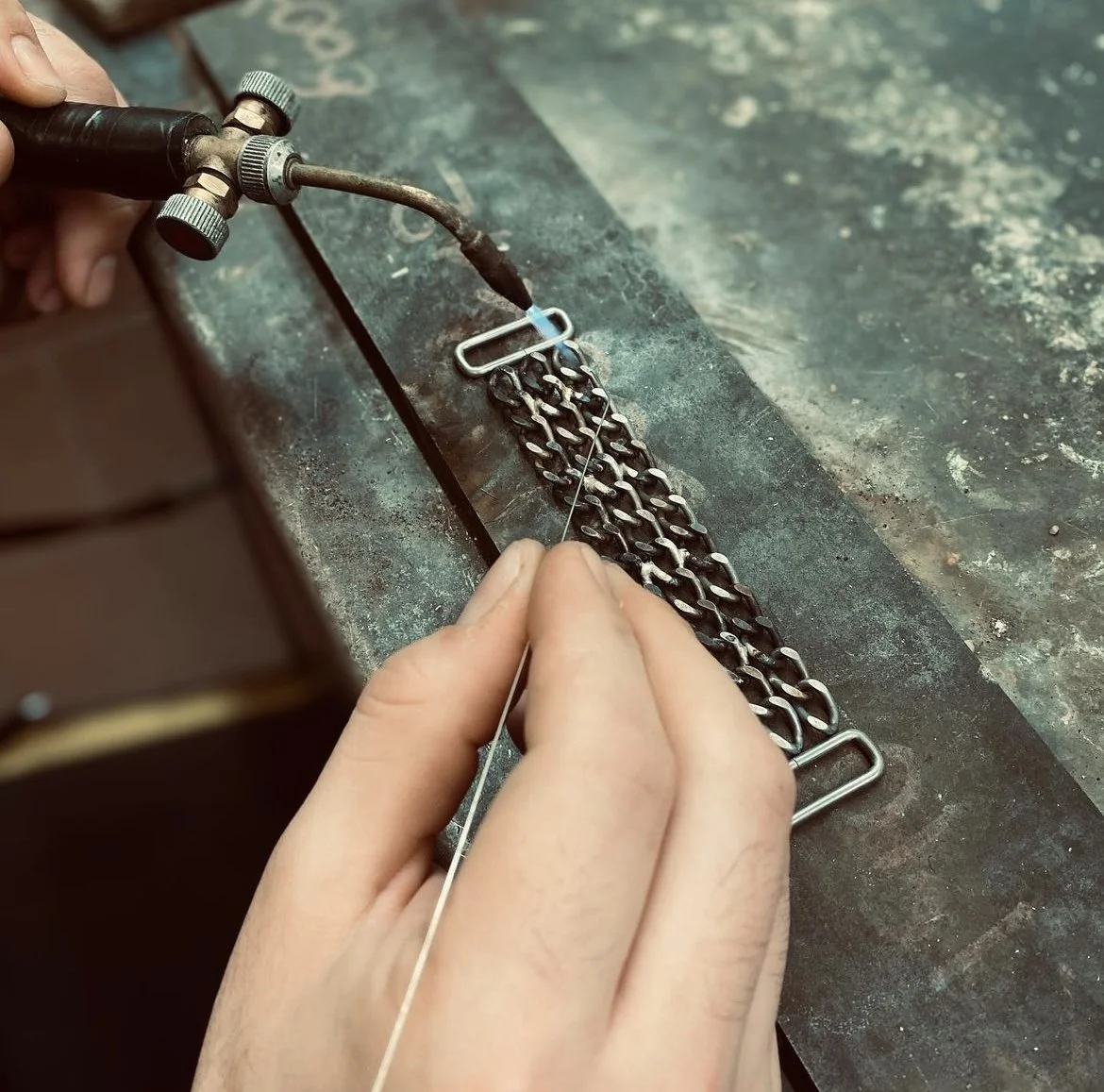 Persona che lavora con una pistola saldatrice su una catena di metallo
